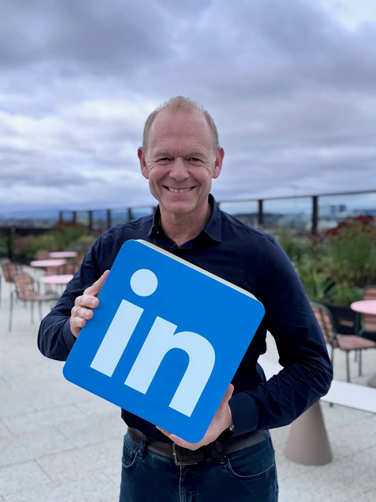 Peter von Wartenberg hält ein großes LinkedIn-Logo in den Händen
